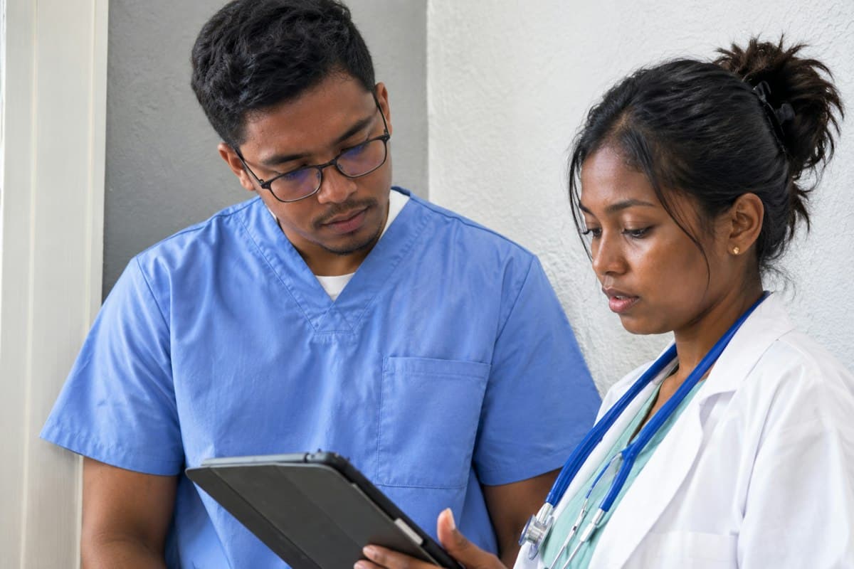 Un infirmier et une médecin consultent ensemble un dossier de soins sur une tablette